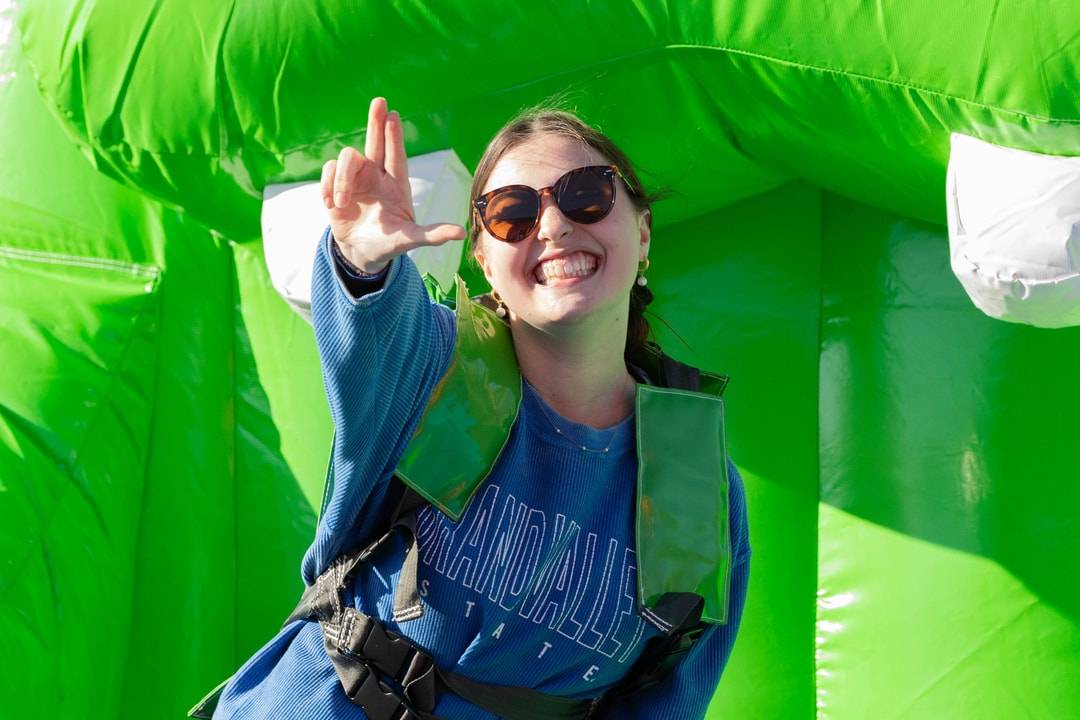 Student doing the "Anchor Up" hand signal while on a green inflatable